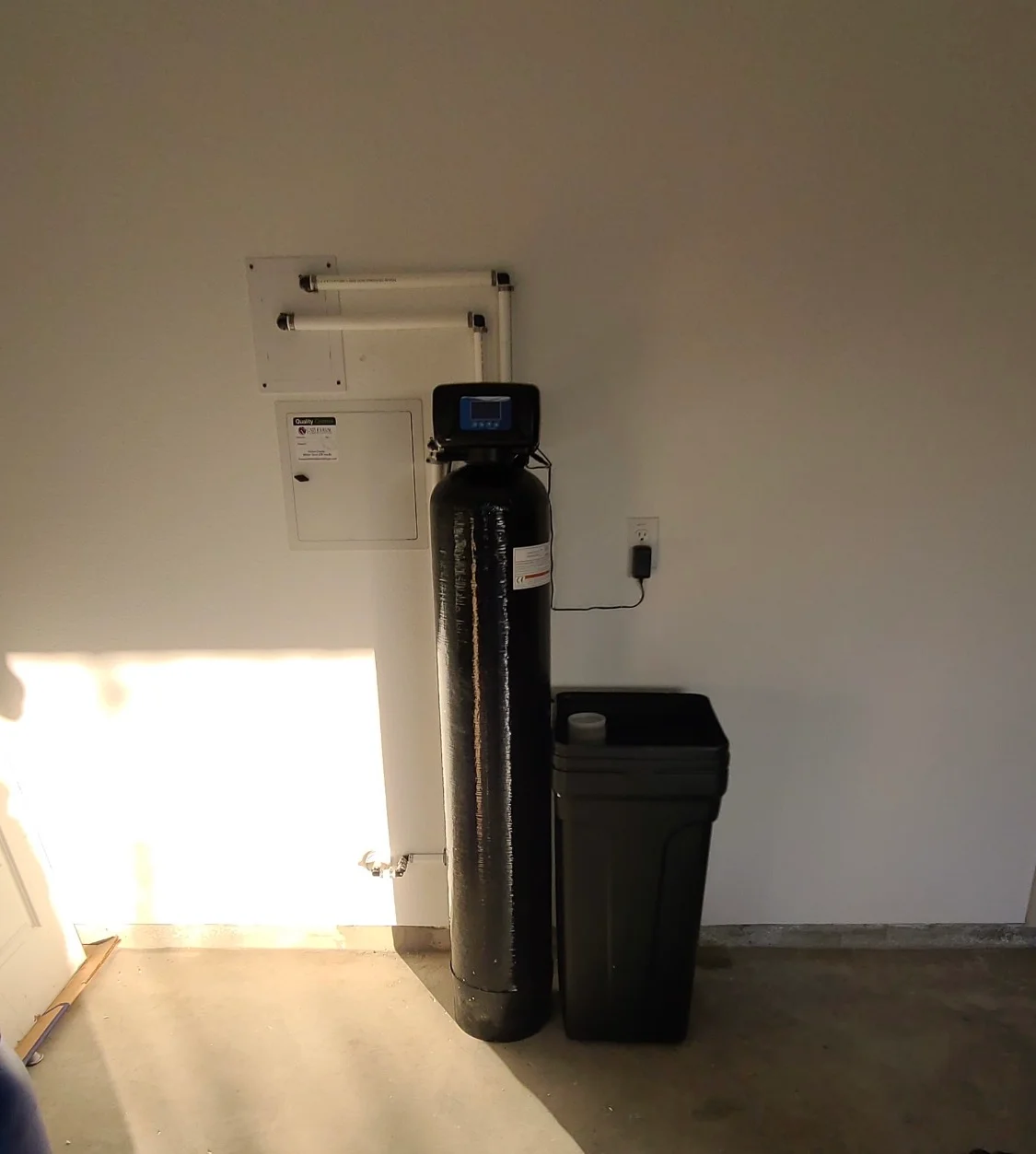 Installed water softener system with black resin tank and digital control display Installed water softener system with black resin tank and digital control display