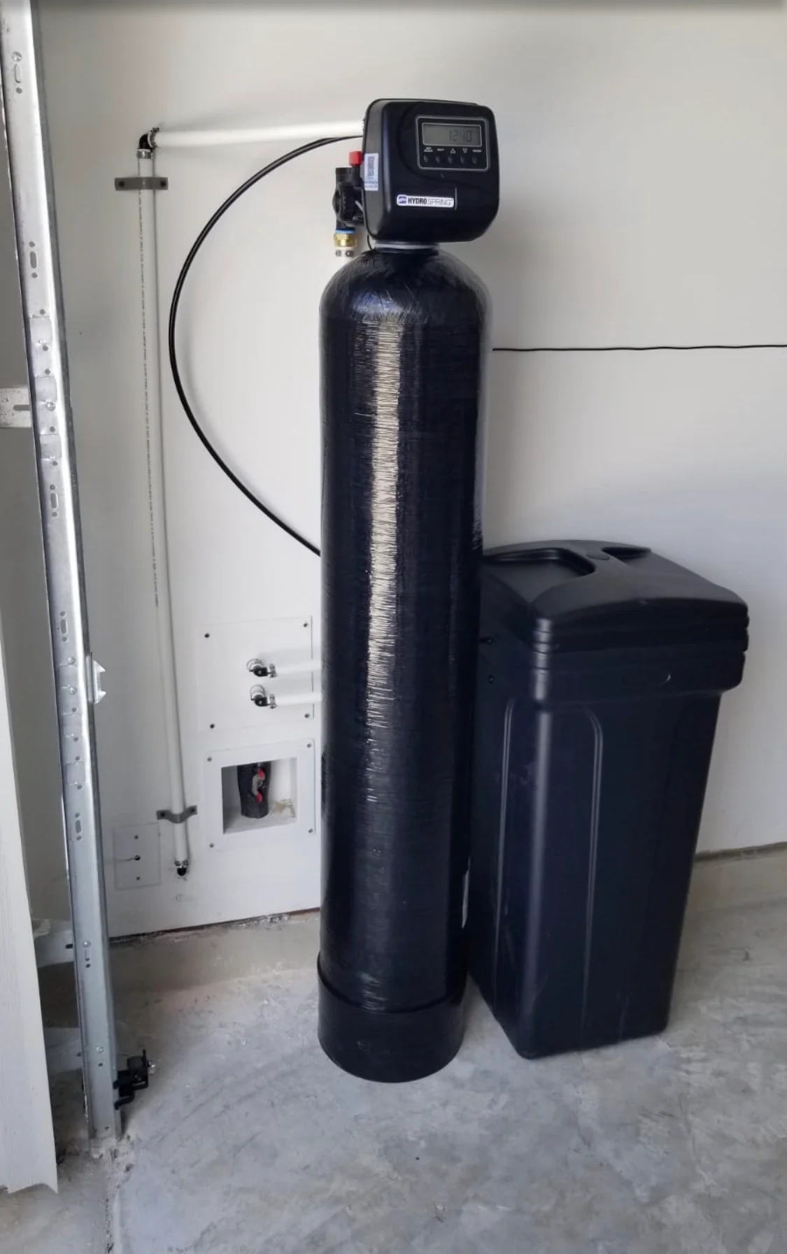 Black water softener tank with digital control valve and brine tank installed in utility room Black water softener tank with digital control valve and brine tank installed in utility room